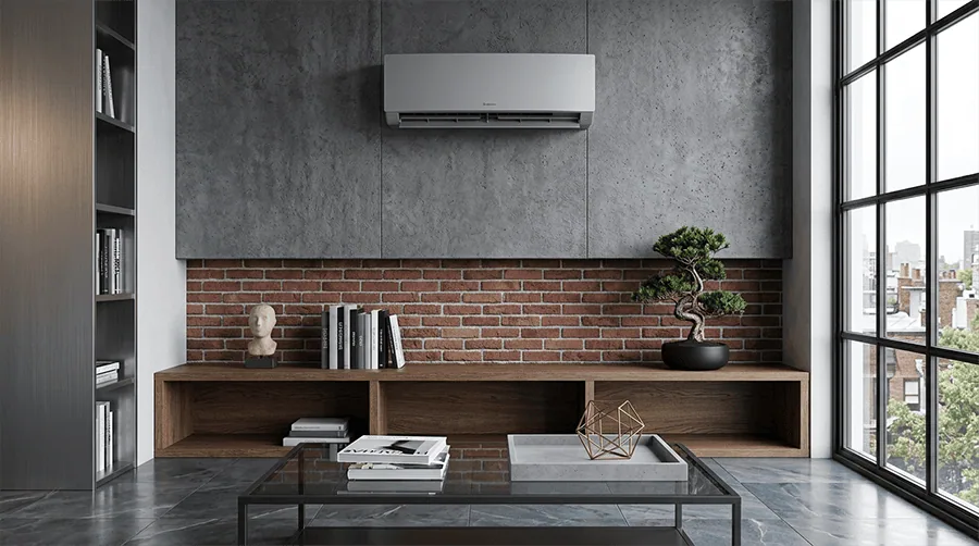 Ein modernes Wohnzimmer mit wandmontierter Klimaanlage, Ziegelwand, dunklen Möbeln, Bonsai und großem Couchtisch vor den Fenstern.
