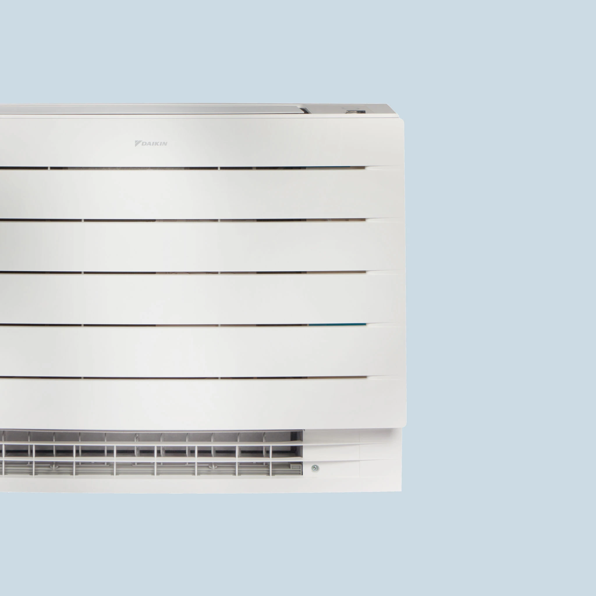 Das weiße Daikin Truhengerät zeigt eine schlichte Front mit breiten Lamellen und sichtbarem Lüftungsgitter am unteren Rand.